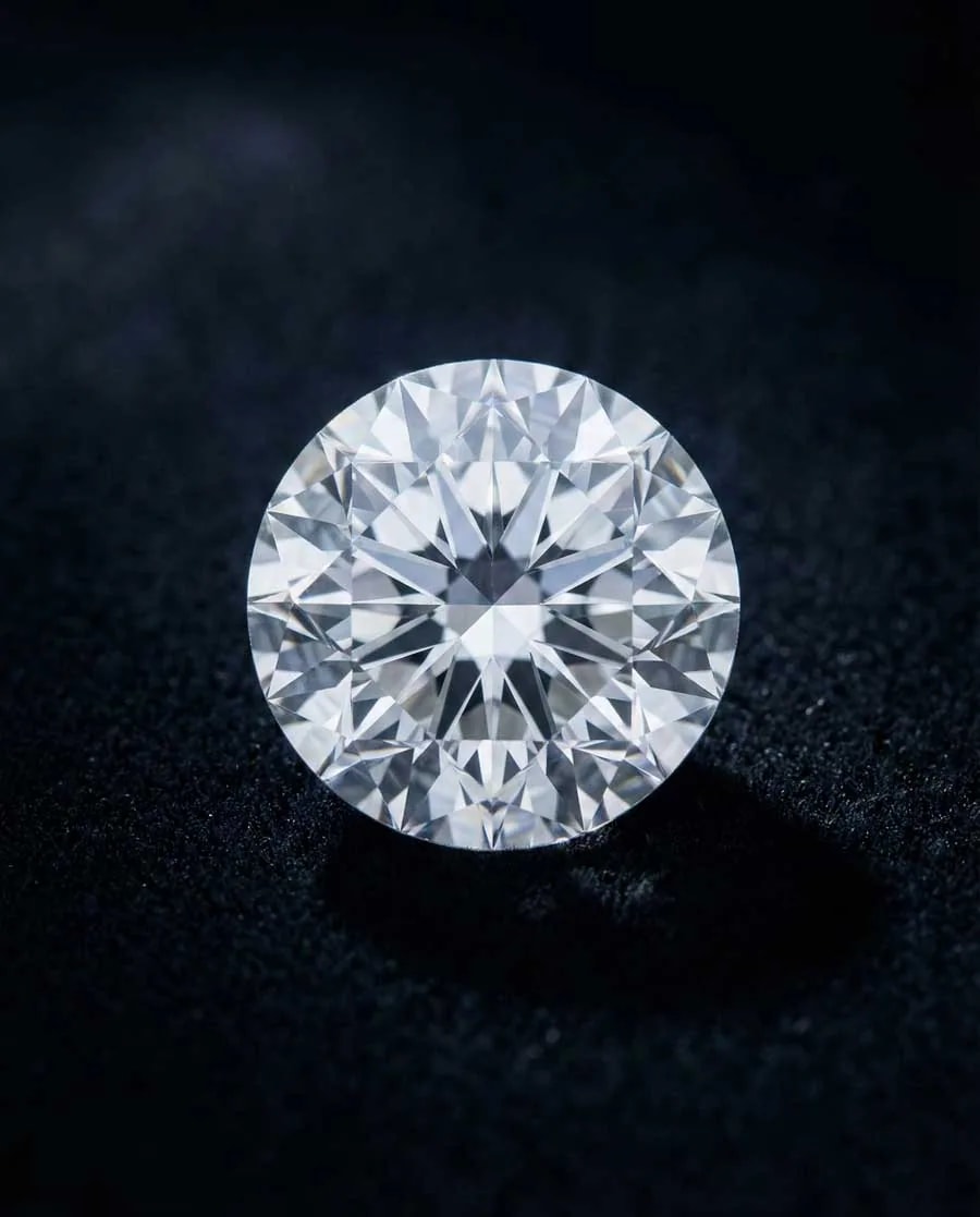 Diamant incolore taille brillant sur velours noir élégant, éclairage latéral dramatique révélant le feu et l'éclat avec dispersion de lumière arc-en-ciel
