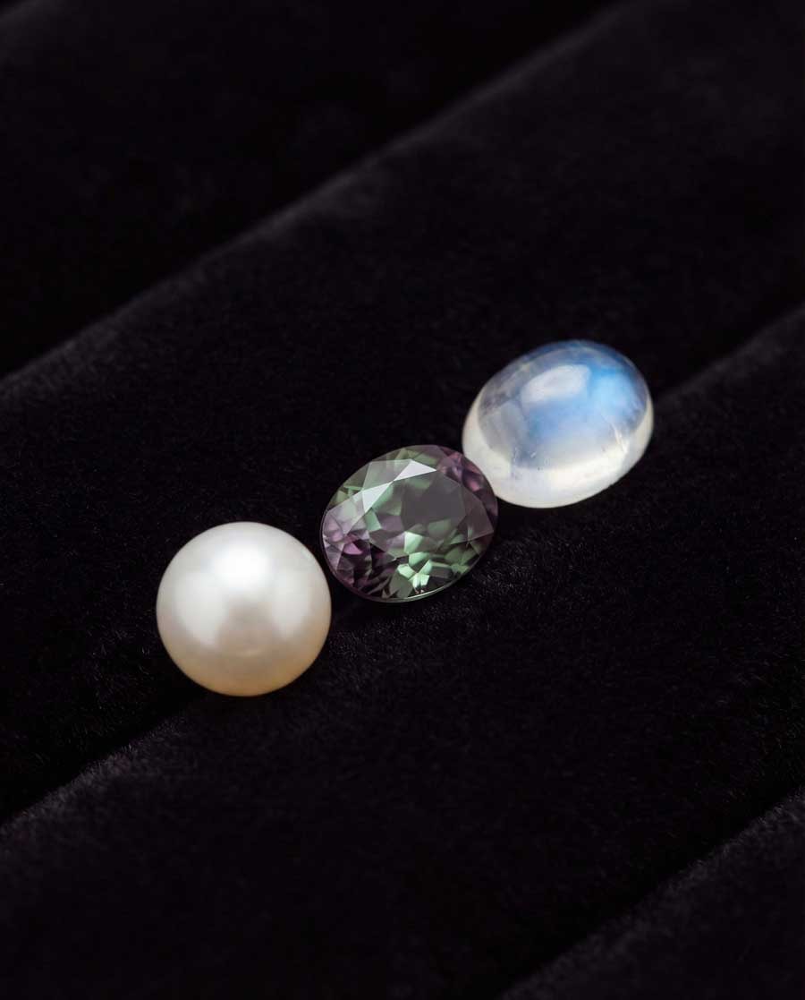 June birthstones comparison: pearl strand, color-changing alexandrite, and blue moonstone with adularescence