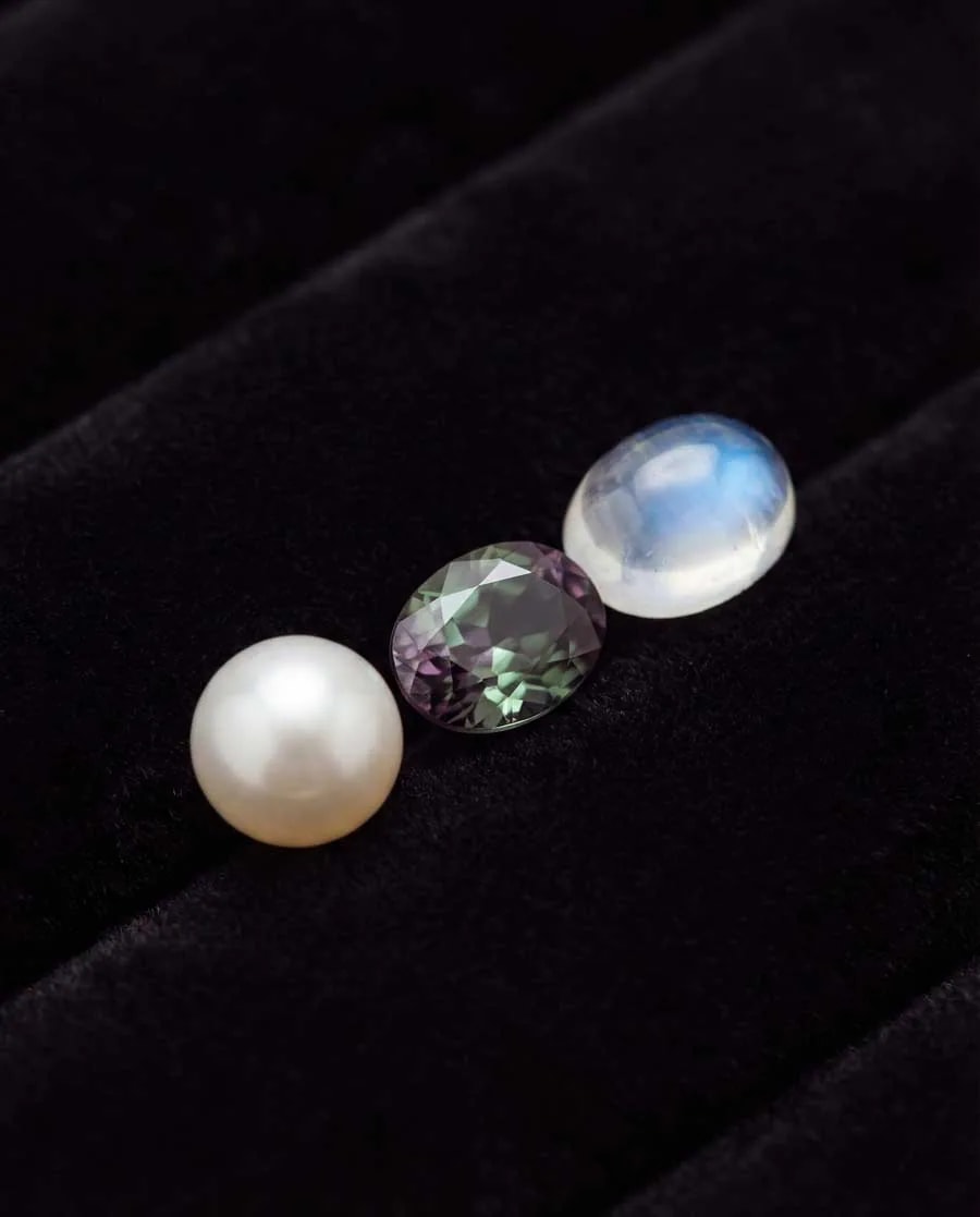 Comparaison des pierres de naissance de juin : collier de perles, alexandrite aux reflets changeants et pierre de lune bleue à adularescence