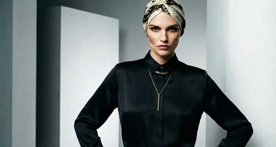 Un modèle démontrant comment superposer des colliers avec un haut à col en V, montrant un ras du cou court et un collier avec pendentif plus long qui complète le décolleté.