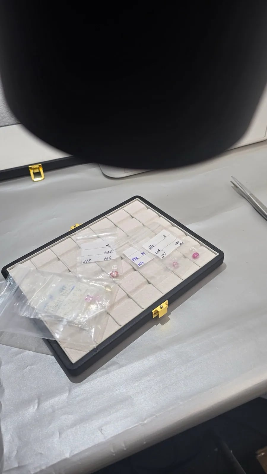 Loose gemstones handled with tweezers on a sorting table before cleaning and certification