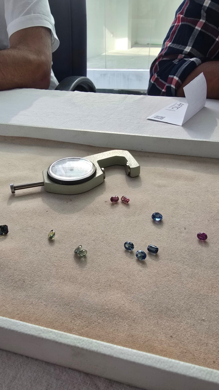 Loose colored sapphires and a measuring gauge on a gem tray during selection