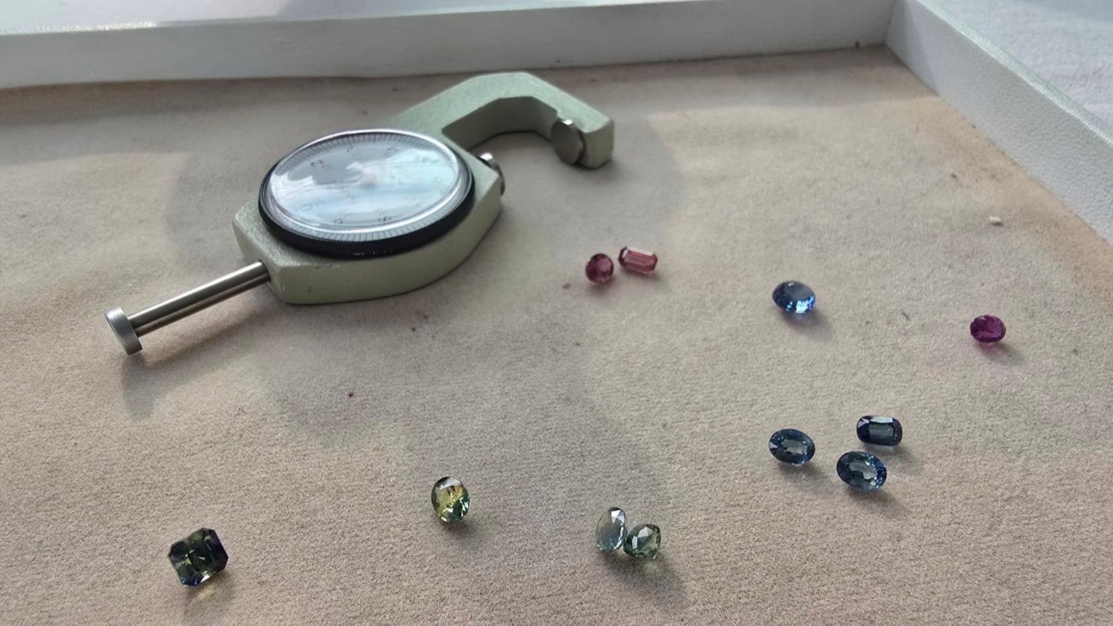 A spread of loose sapphire colors, pink, blue, green, teal and violet, on a gem tray