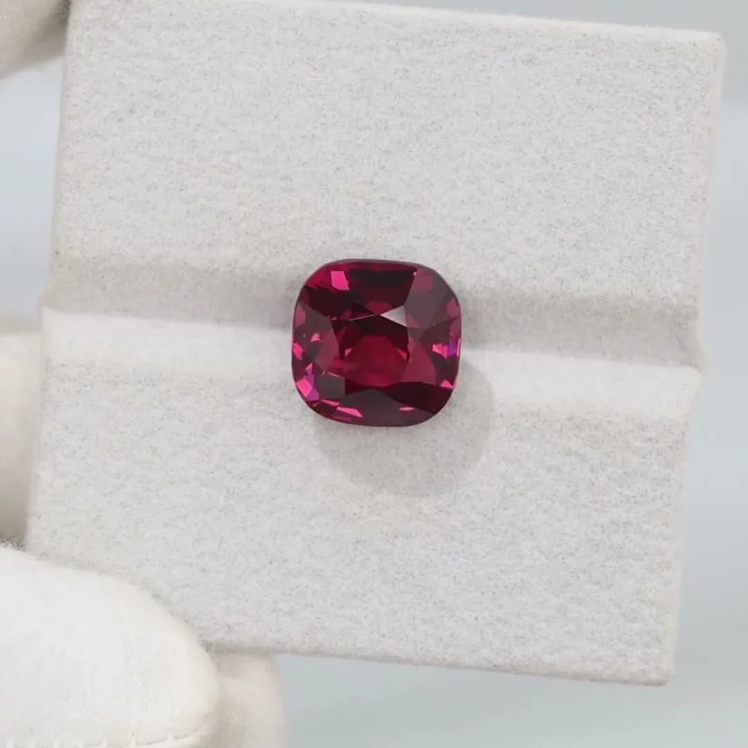 14-carat rhodolite garnet cushion held in a gloved hand