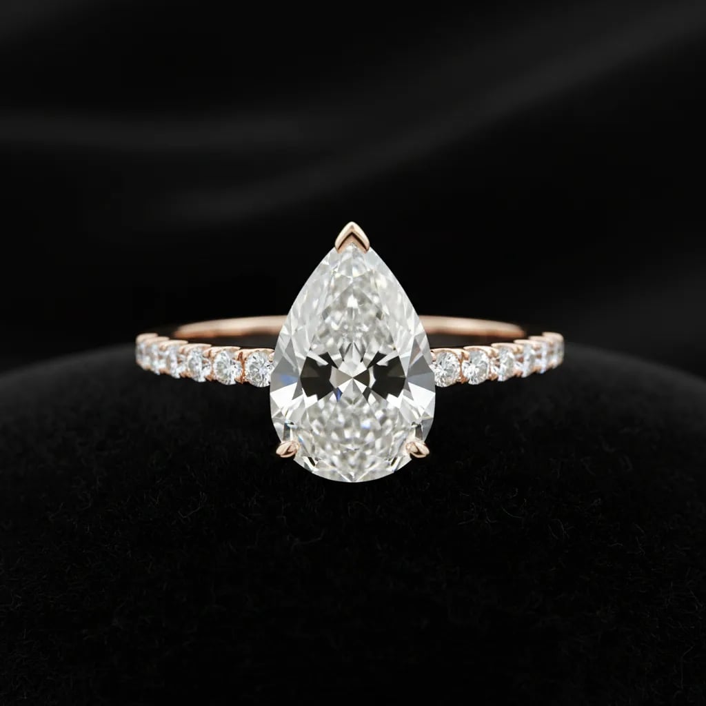 A pear cut diamond in a rose gold pave band showing a faint dark bow tie band across the centre of the stone
