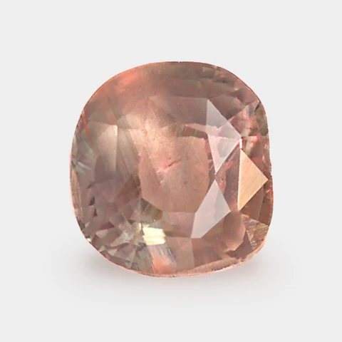 La même alexandrite, taille coussin, 0,90 ct, qui paraît d’un rose brunâtre sous la lumière d’une lampe chaude, sur fond gris