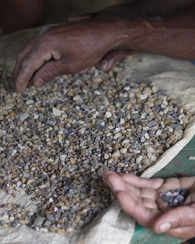 Two hands sorting washed gem gravel spread on a jute sack