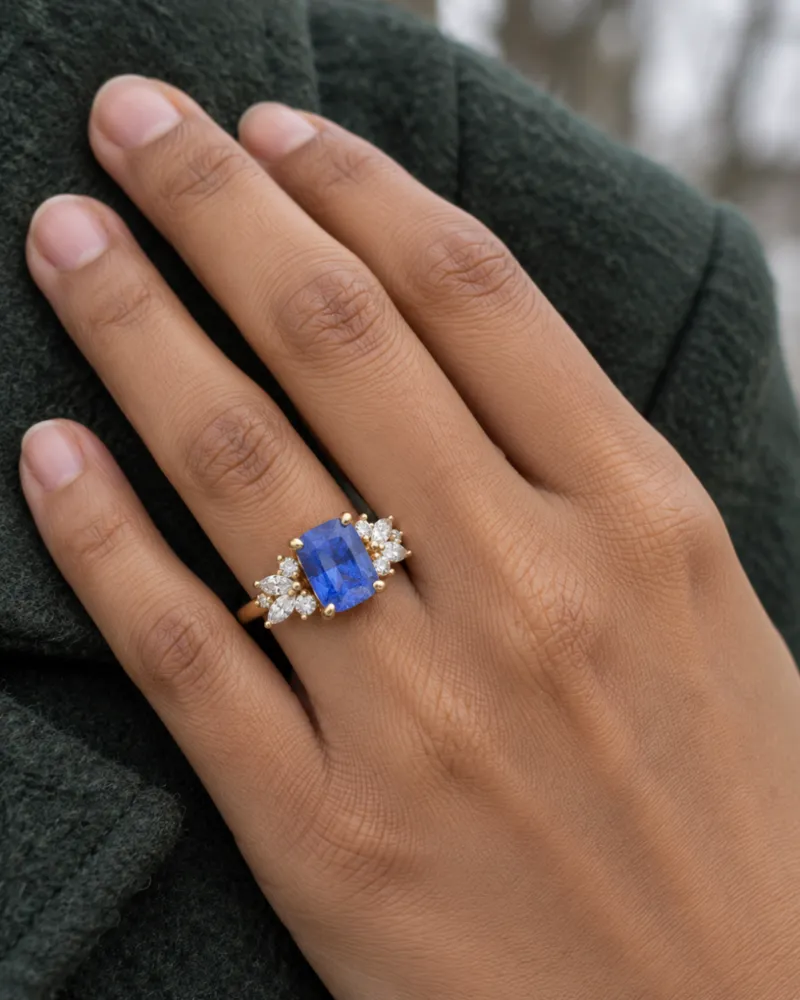 Illustration of a blue sapphire engagement ring, Radiant style, worn on a hand.