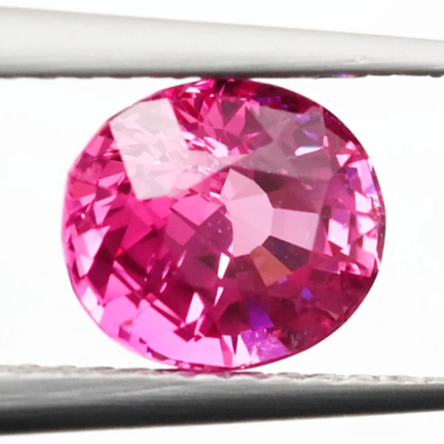 Loose sapphire listed as pink, 2.01 ct, oval cut, held in tweezers on a light grey ground